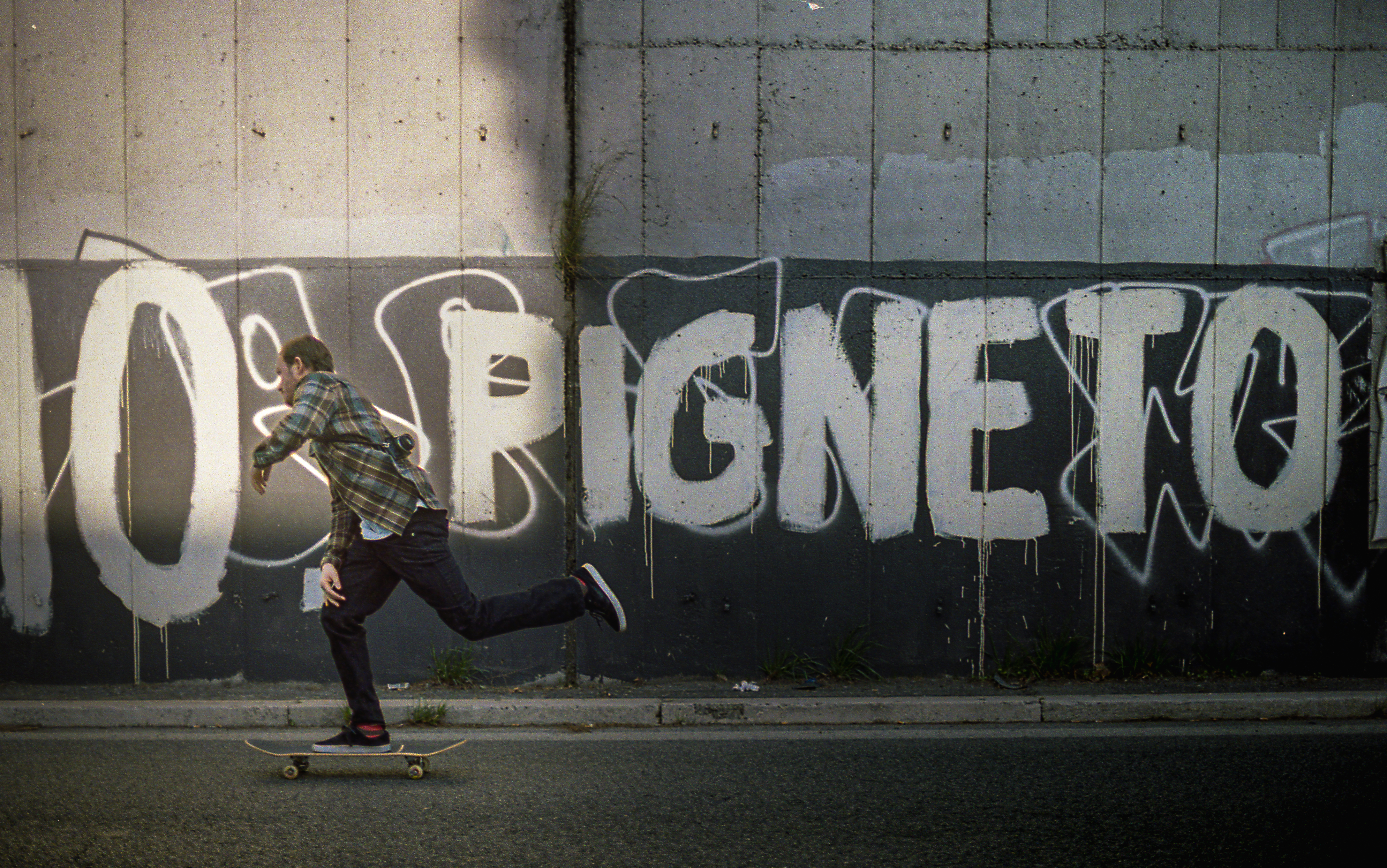 Skateboarder passing a graffiti-covered wall